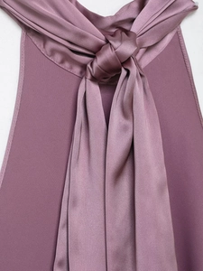 Close-up of knotted halter detail on purple satin top showing smooth fabric texture