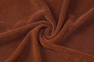 Close-up detail of rust red fine ribbed knit fabric showing texture and soft drape