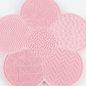 Macro detail of pink flower silicone makeup brush cleaning mat with varied scrubbing textures