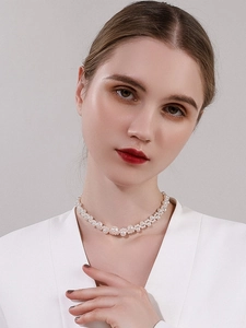 Detailed view of layered faux pearl choker necklace worn on model with white blazer