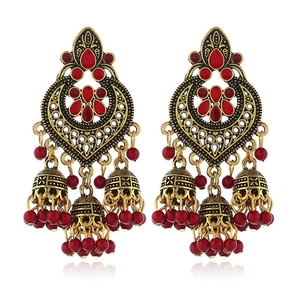 Detail of golden bohemian Jhumka earrings with red gemstones and dangling beads