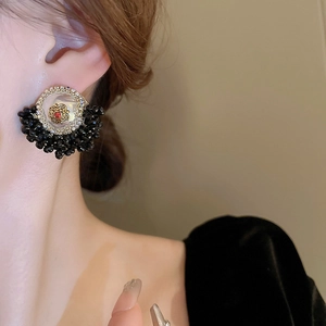 Detail of vintage flower stud earrings with red crystal and black beads on female model