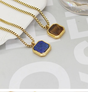 Detailed macro view of square tiger eye and lapis lazuli pendants on gold box chains