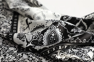Macro shot of black and white paisley silk scarf showing soft folds and glossy texture
