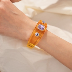 Macro detail of amber resin bracelet featuring purple gemstones and diamond inlay