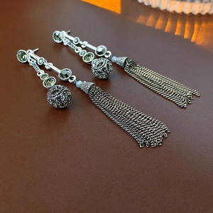 Dettaglio di orecchini vintage a nappa con cristalli verdi e sfere di metallo traforate