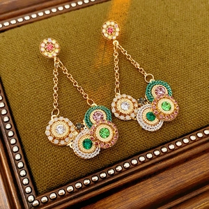 Détail de boucles d'oreilles vintage en or avec pierres colorées sur velours vert