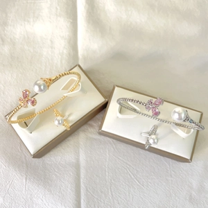 Detailed close-up of open butterfly pearl bangle and ring sets in gold and silver finish