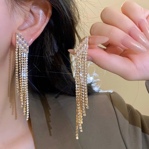 Close-up of elegant gold plated long tassel earrings with sparkling rhinestones on model