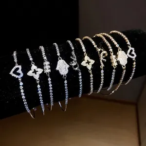 Elegant zircon charm bracelet with clover, heart and bow pendants on black velvet display