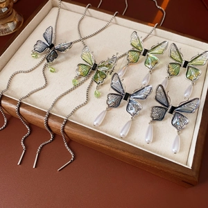 Detailed close-up of crystal butterfly necklaces and pearl earrings on a tray