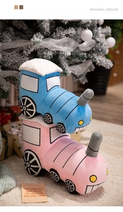 Detail of plush cartoon train toys in pink and blue under a festive Christmas tree