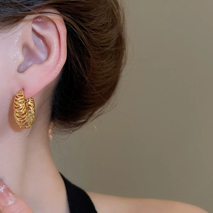 Gros plan de créoles plaquées or 18 carats avec texture tressée portées par un mannequin