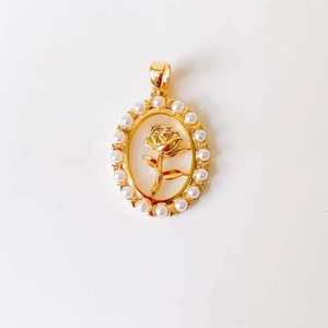 Close-up of golden oval pendant featuring a rose relief and pearl border detailing