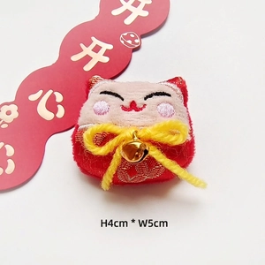 Detail view of 4x5cm plush Japanese cat charm with embroidery and golden bell accent
