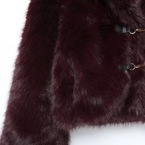 Dettaglio del cappotto di pelliccia sintetica bordeaux con texture morbida e fibbia in pelle