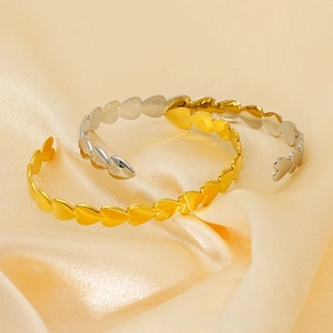 Detail of gold and silver heart-shaped open bracelets with matte brushed metal texture