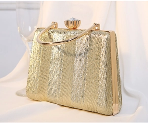 Detail of gold pleated evening clutch with crystal clasp and elegant metallic handle