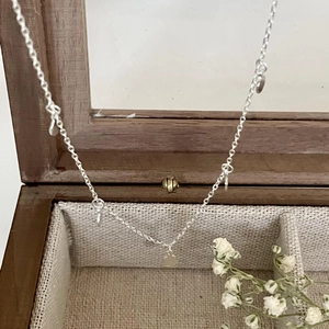 Elegant 925 sterling silver necklace with mini round charms on a wooden jewelry box
