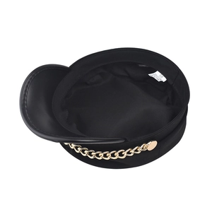 Detail view of black newsboy hat featuring a gold chain and cotton fabric inner lining