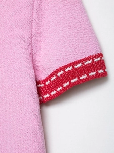 Detailed macro view of pink knit sleeve with red contrast edging and white stitching
