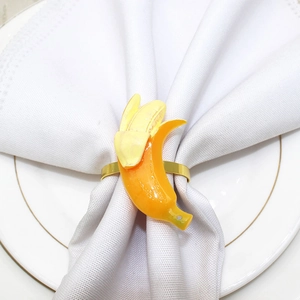 Macro detail of a banana-shaped resin napkin ring on a white cloth with gold ring