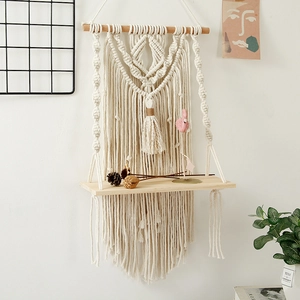 Detail of bohemian macrame wall shelf with hand-woven cotton rope and wood tray