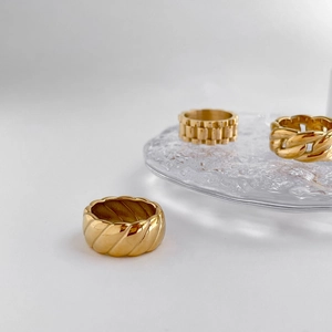Nahaufnahme goldener breiter Ringe mit Kordel-, Ketten- und Uhrenarmband-Texturen
