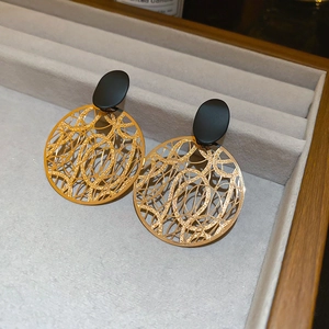 Detail goldene hohle Creolen mit schwarzem ovalem Stecker auf grauem Samttablett