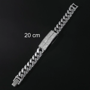 Close-up of a silver Cuban link bracelet with a sparkling gemstone ID plate and box clasp