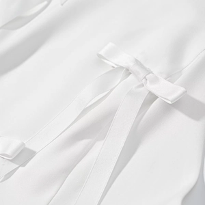Gros plan sur la texture du sergé blanc et le détail du nœud sur le haut dos nu