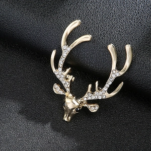 Close-up of golden elk brooch with sparkling white rhinestones on black leather background