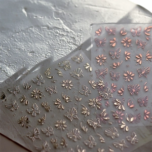 Macro detail of metallic butterfly nail art stickers in gold and rose gold finishes