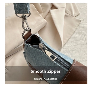 Detail of vintage denim shoulder bag with smooth silver zipper and leather trim