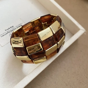 Detail of tortoiseshell resin blocks and polished gold metal segments of the wide bangle