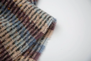 Detailed close-up of plaid weave texture with frayed edges on a winter shawl
