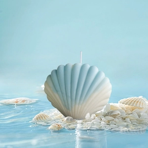 Gros plan d'une bougie en forme de coquillage dégradé bleu sur fond de mer clair