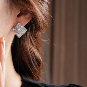 Gros plan de boucles d'oreilles carrées en argent avec zircons brillants sur un modèle