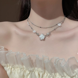 Detailed close-up of double-layer necklace with white flower and pearl embellishments