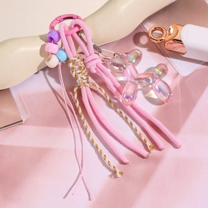 Détail d'un porte-clés tissé rose avec chien ballon iridescent et perles colorées