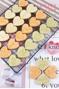Close-up of heart-shaped cookies with LOVE and KISS 3D embossing on a metal cooling rack