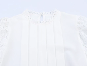 Close-up of elegant white blouse with lace trim, pleated chest design and round neckline