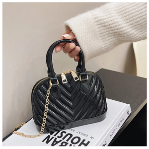 Macro detail of black shell bag with V-shaped wavy texture and golden metal zipper