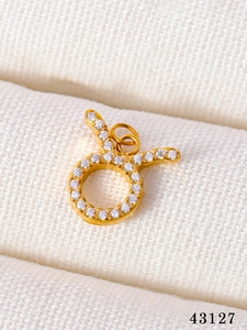 Detail of a gold Taurus zodiac charm pendant with sparkling micro-pave crystals