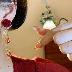 Close-up of red velvet rose earrings with long fringe tassels and pearl beads