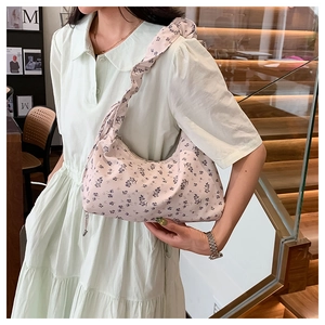 Detail of floral canvas bag with ruffled shoulder strap and crescent moon shape