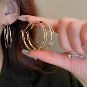Detail of large gold and silver hoop earrings featuring a modern twisted metal texture