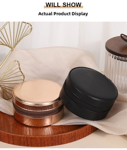 Detail of round PU leather jewelry boxes in rose gold and black on a wooden tray