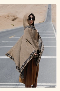 Close-up of hooded brown poncho with tribal patterns in a desert road setting