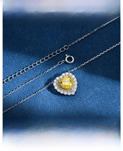 Macro shot of a heart-shaped yellow diamond pendant with diamond halo on silver O-chain